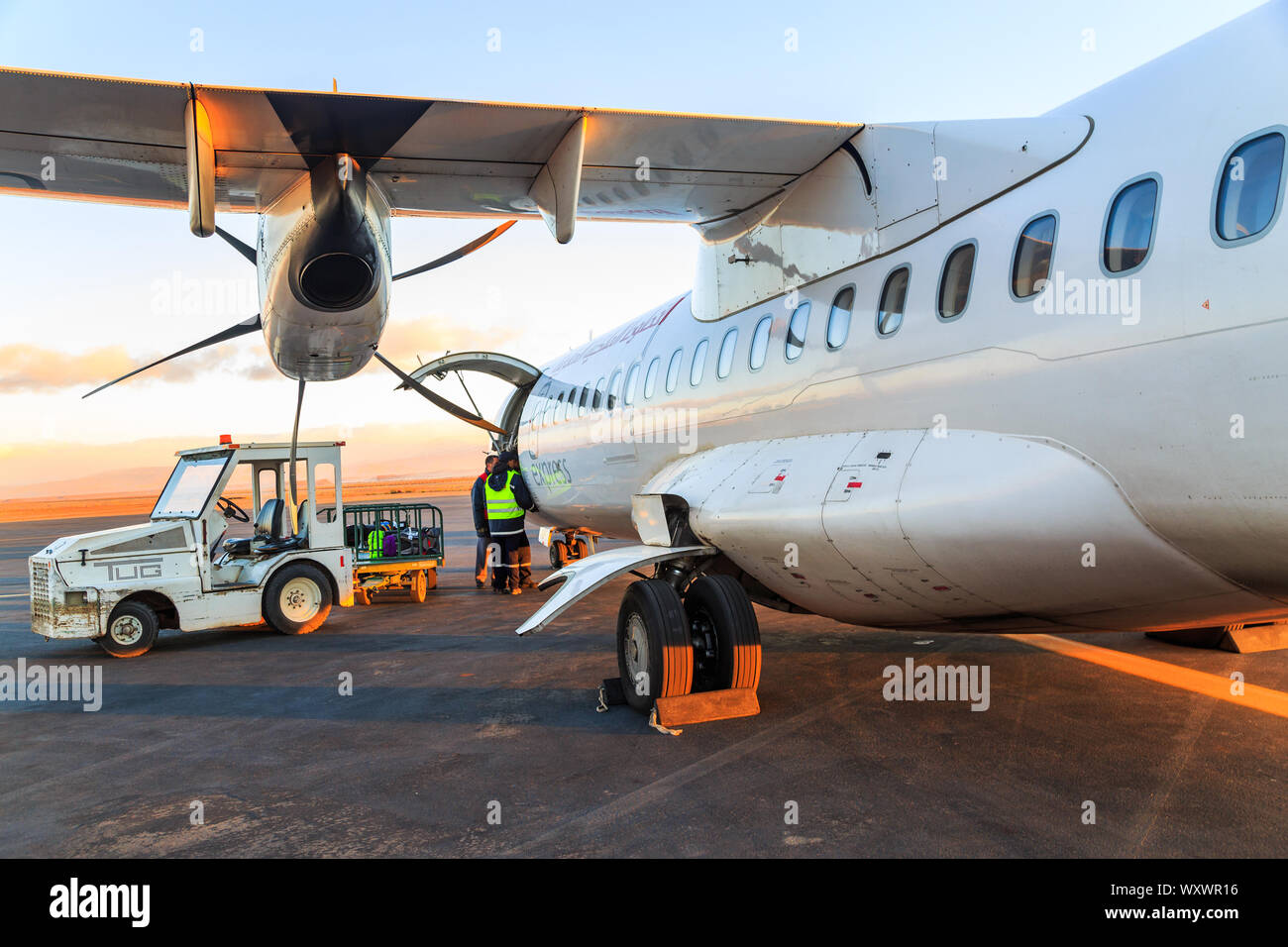 Ouarzazate, Morocco - Feb 28, 2016: agents of the airline charges passengers' luggages in the hold of the airliner at daybreak Stock Photo