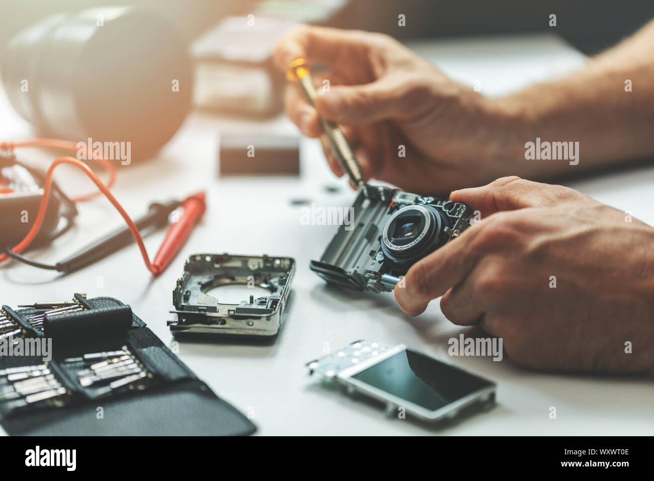 electronic repair service - technician repairing digital camera in office Stock Photo