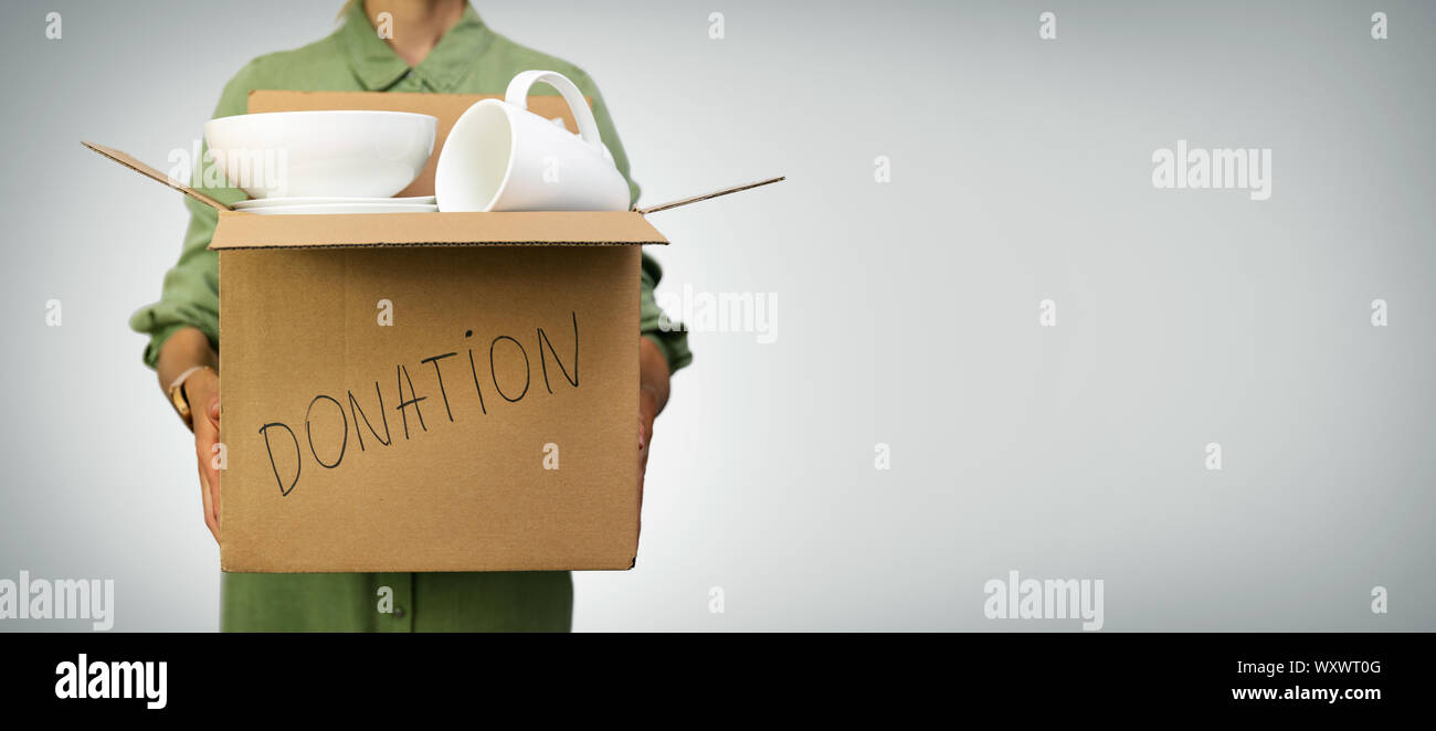 woman holding box with household items for donations on gray background with copy space Stock Photo
