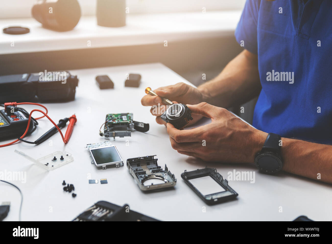 technician repairing broken digital camera lens in office Stock Photo