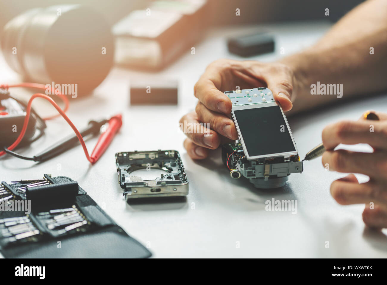 electronic device repair service - man installing new display to digital camera Stock Photo