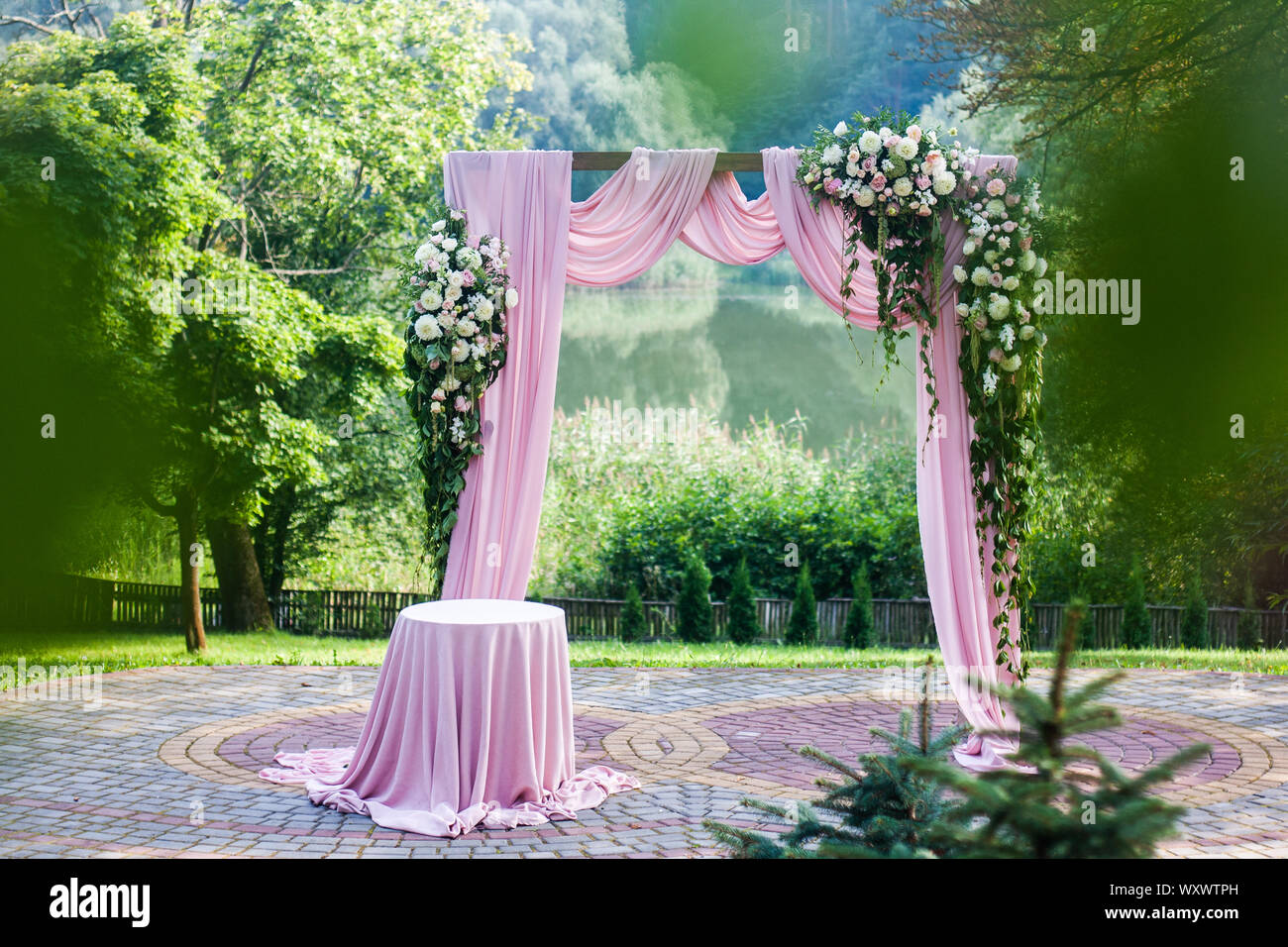 Pink wedding arch with floral white and pink decorations outside in green summer garden Stock Photo