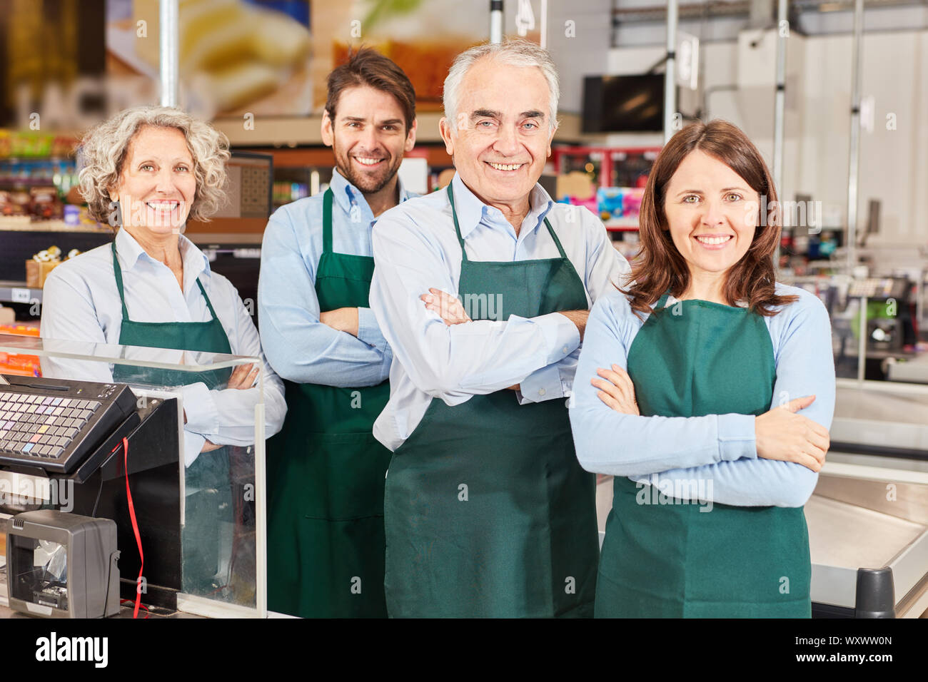 Group of smiling salesmen with market manager and trainee at supermarket checkout Stock Photo