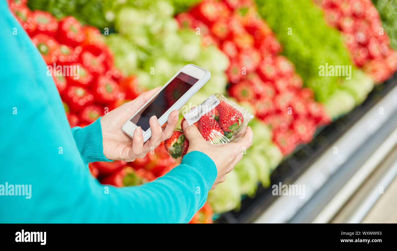 Customer uses barcode scanner app in supermarket while shopping  strawberries Stock Photo - Alamy