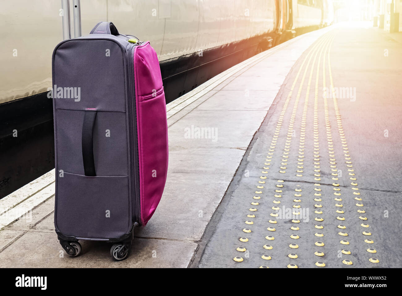 Suitcase standing on the train platform Stock Photo