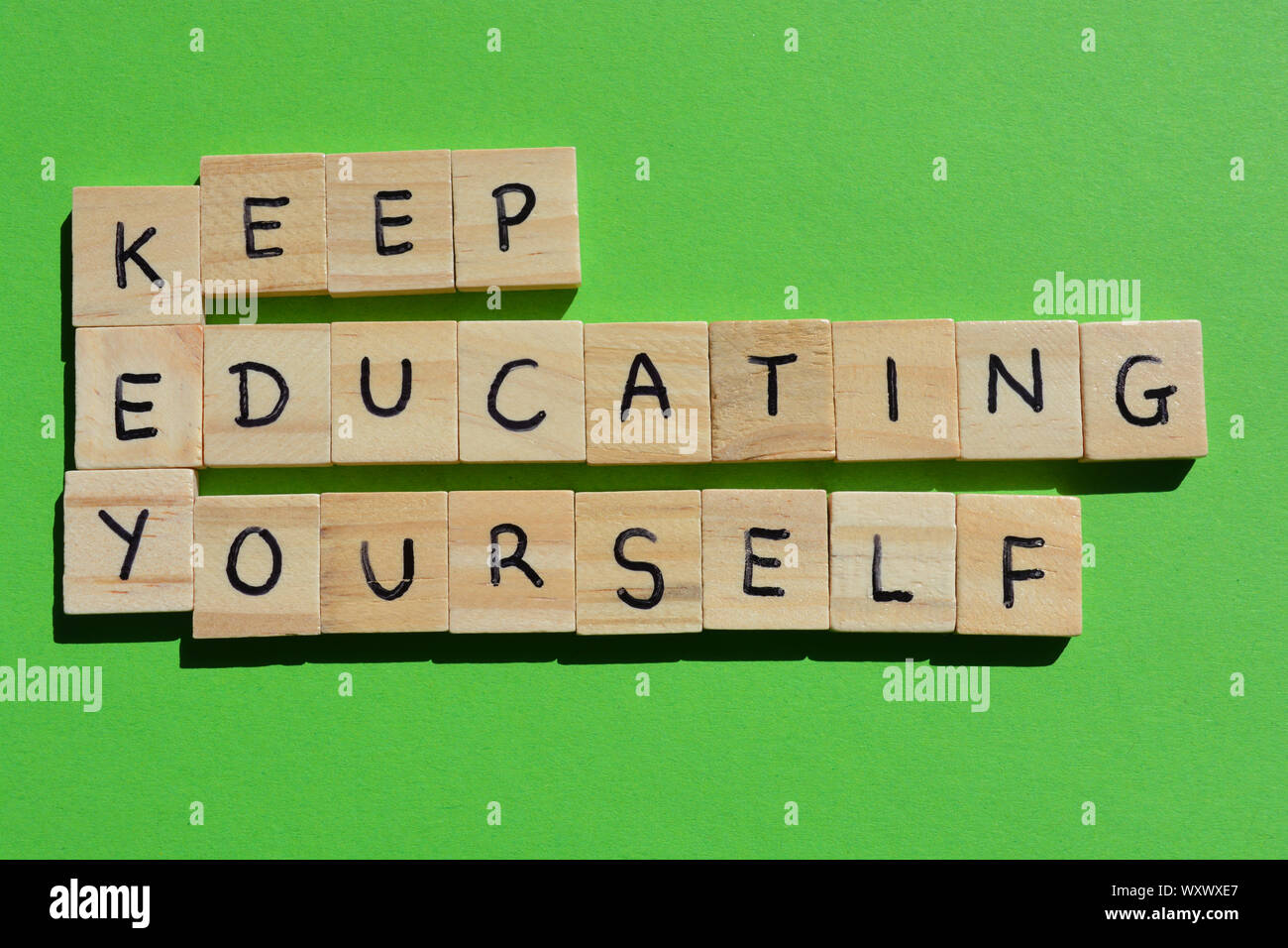 Keep Educating Yourself. Motivational words, using the acronym KEY. Wooden alphabet letters on a bright green background Stock Photo