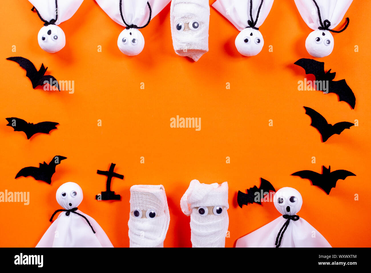 Top view of Halloween crafts, Ghost and bats on orange paper background ...