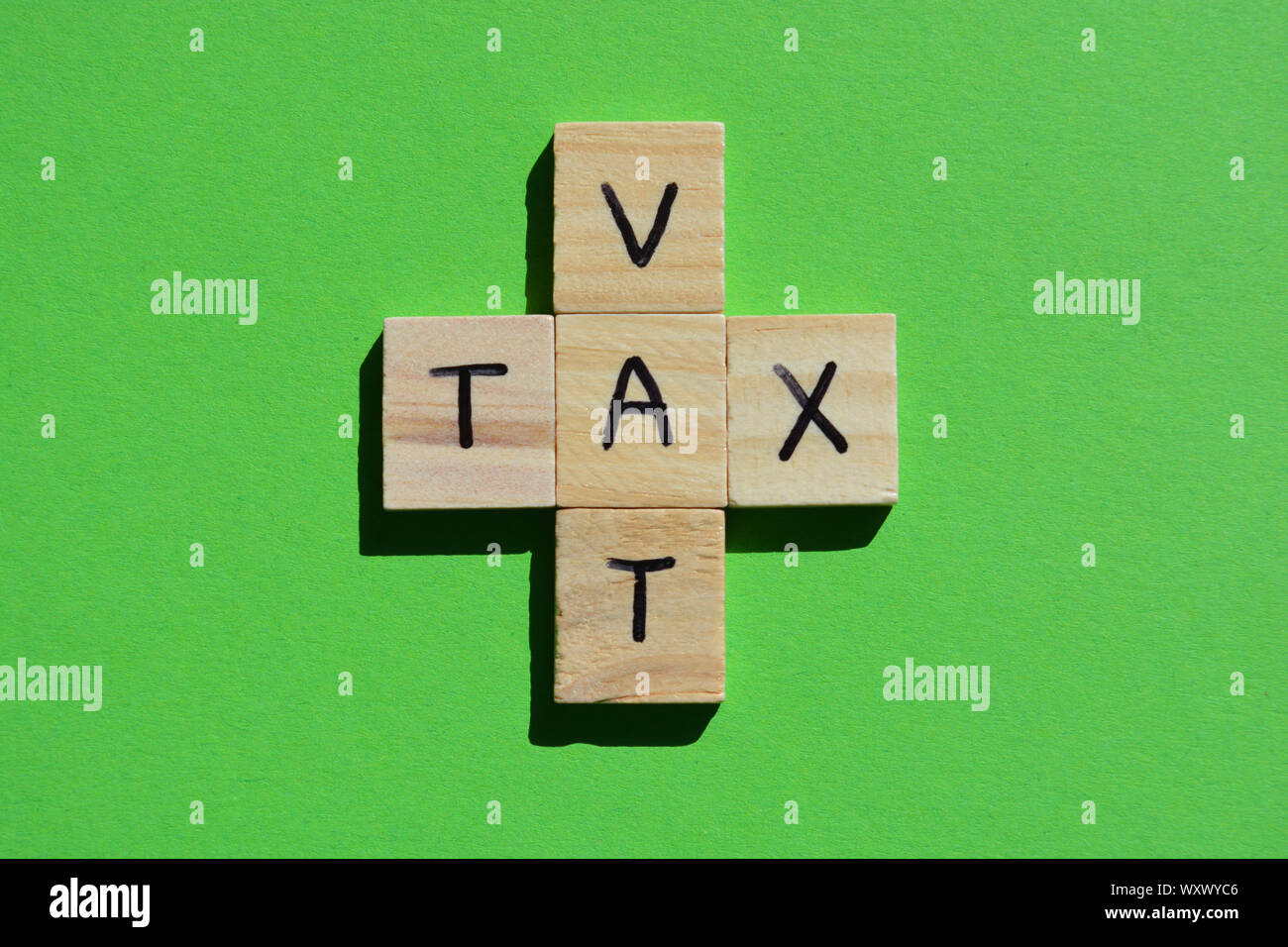 VAT (acronym for Value Added Tax) and Tax in 3d wooden alphabet letters on a bright green background Stock Photo