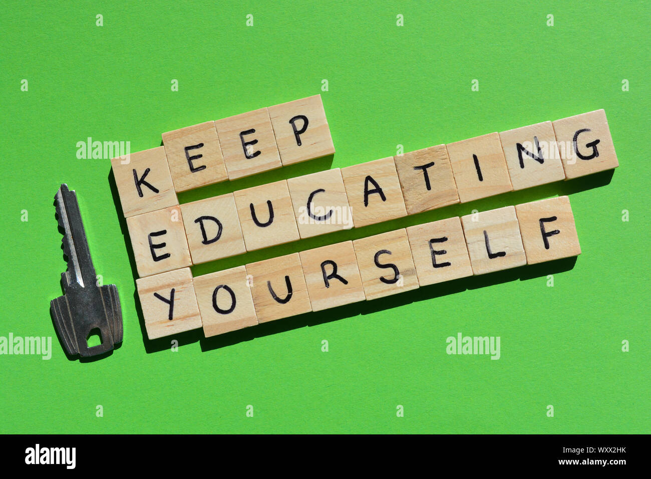 Keep Educating Yourself. Motivational words, using the acronym KEY. Wooden alphabet letters next to a metal key on a green  background Stock Photo