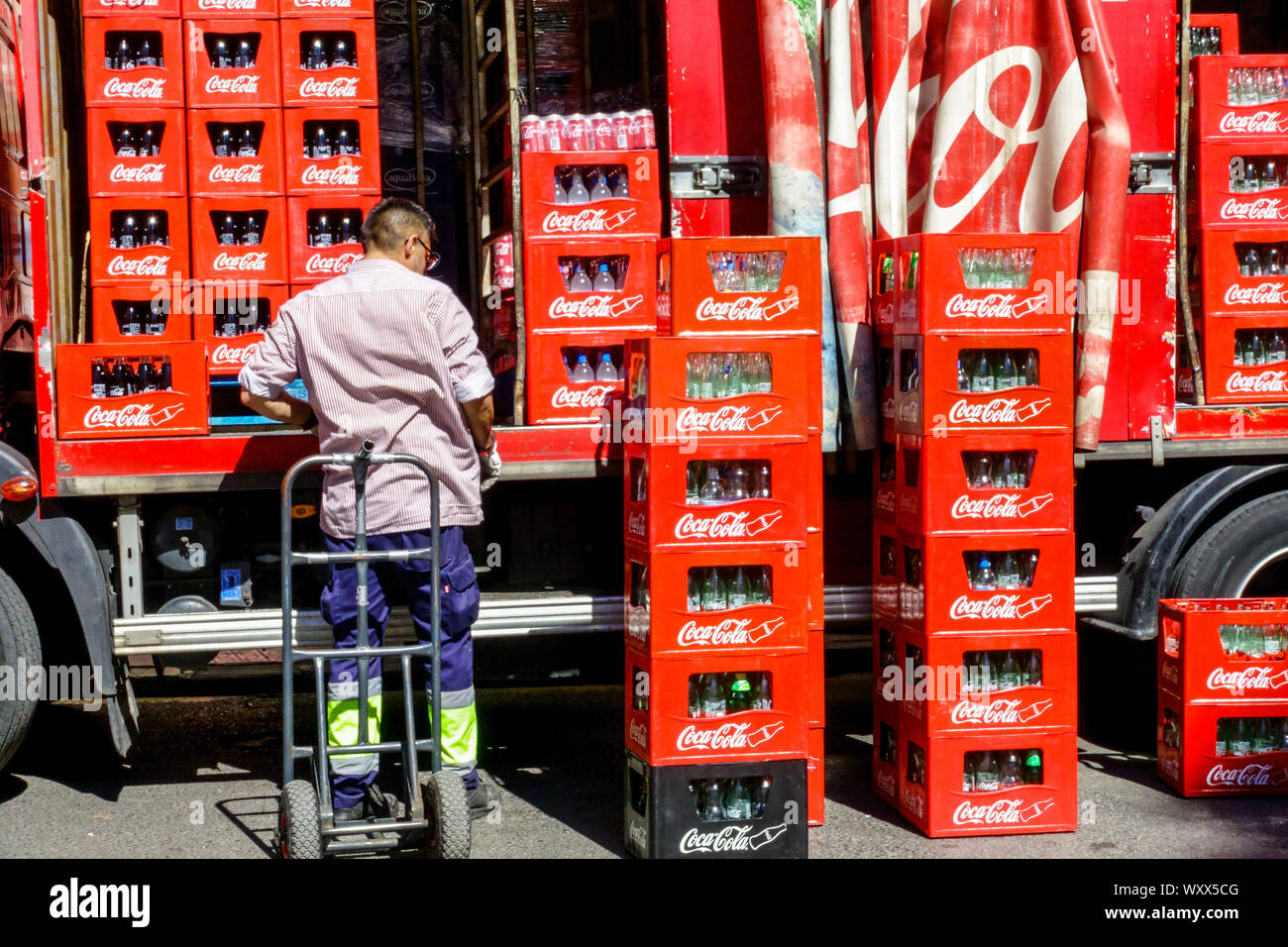 Man delivering bottles in crates from Coca Cola truck, Coca Cola delivery truck Spain Stock Photo