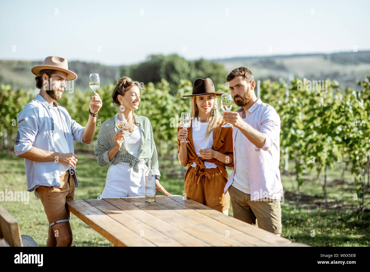 Group of young friends dressed casually having fun together, tasting wine on the vineyard on a sunny summer morning Stock Photo