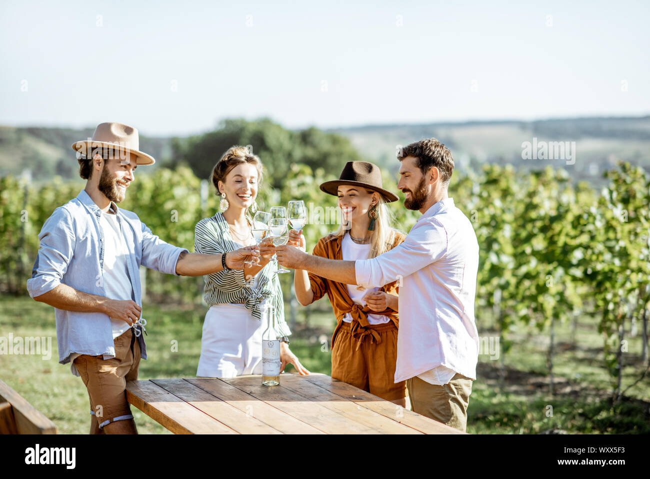 Group of young friends dressed casually having fun together, tasting wine on the vineyard on a sunny summer morning Stock Photo