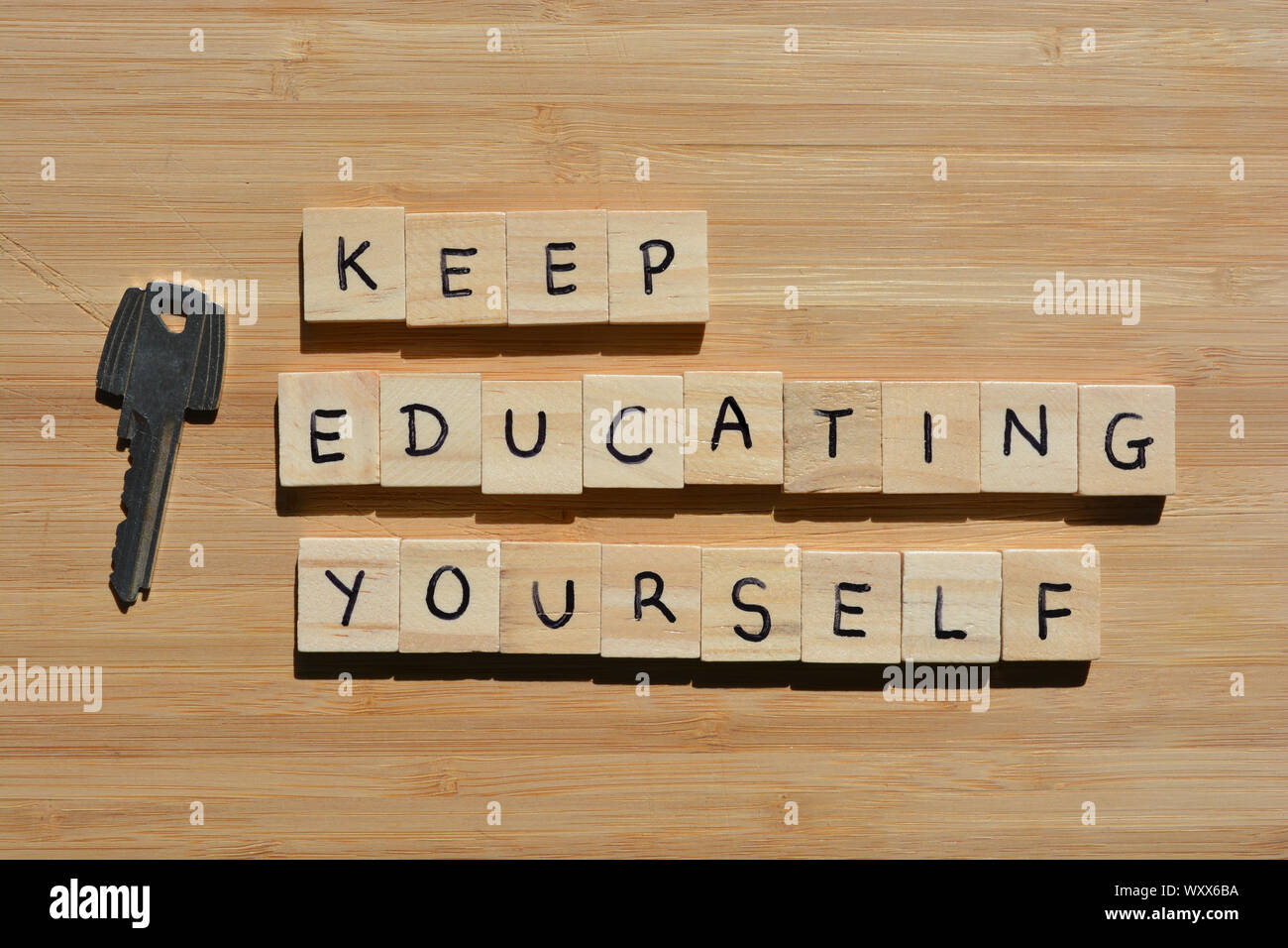 Keep Educating Yourself. Motivational words, using the acronym KEY. Wooden alphabet letters next to a metal key on a wooden background Stock Photo