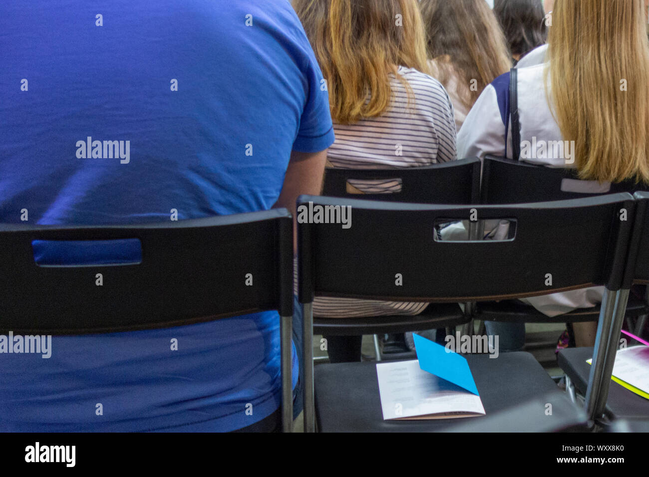 People in auditory during presentation or seminar. Teenagers or young men and women at university lecture or seminar. Back side view with no faces. Th Stock Photo