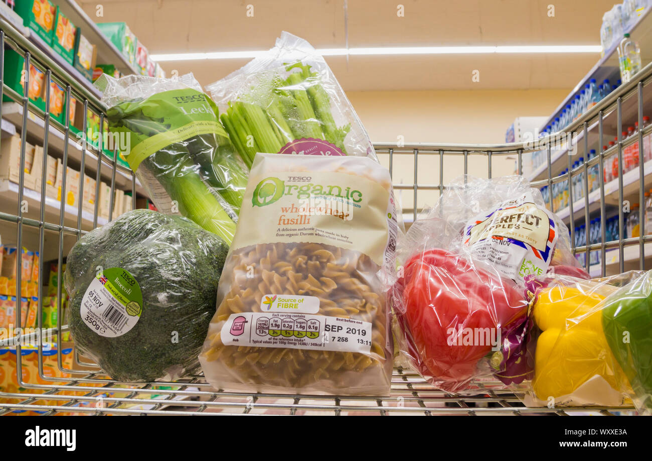 Veg and wholewheat pasta in plastic packaging in shopping trolley. Tesco supermarket UK Stock Photo