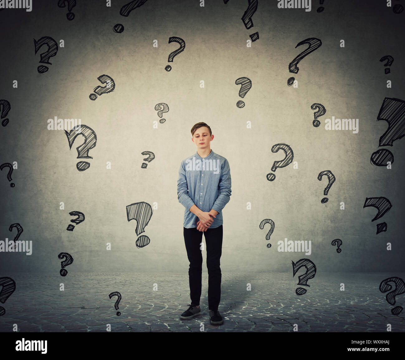 Pensive teenage boy looking down thoughtful as has multiple questions to answer. Boy experiencing adolescence crisis, needs psychological help. Surrou Stock Photo
