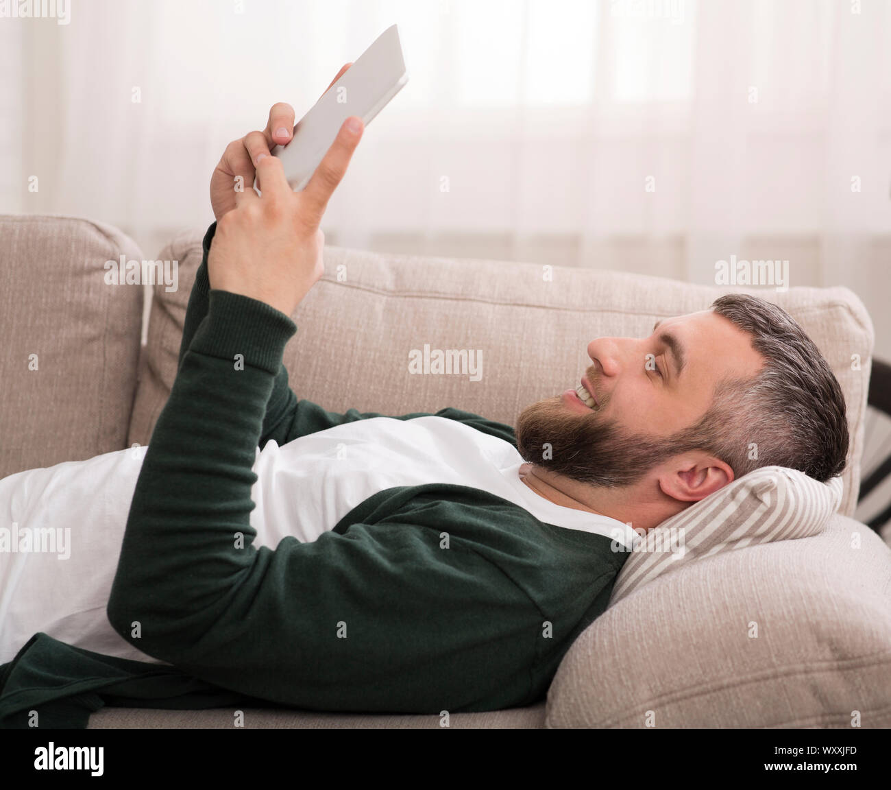 Lazy man using digital tablet at home Stock Photo