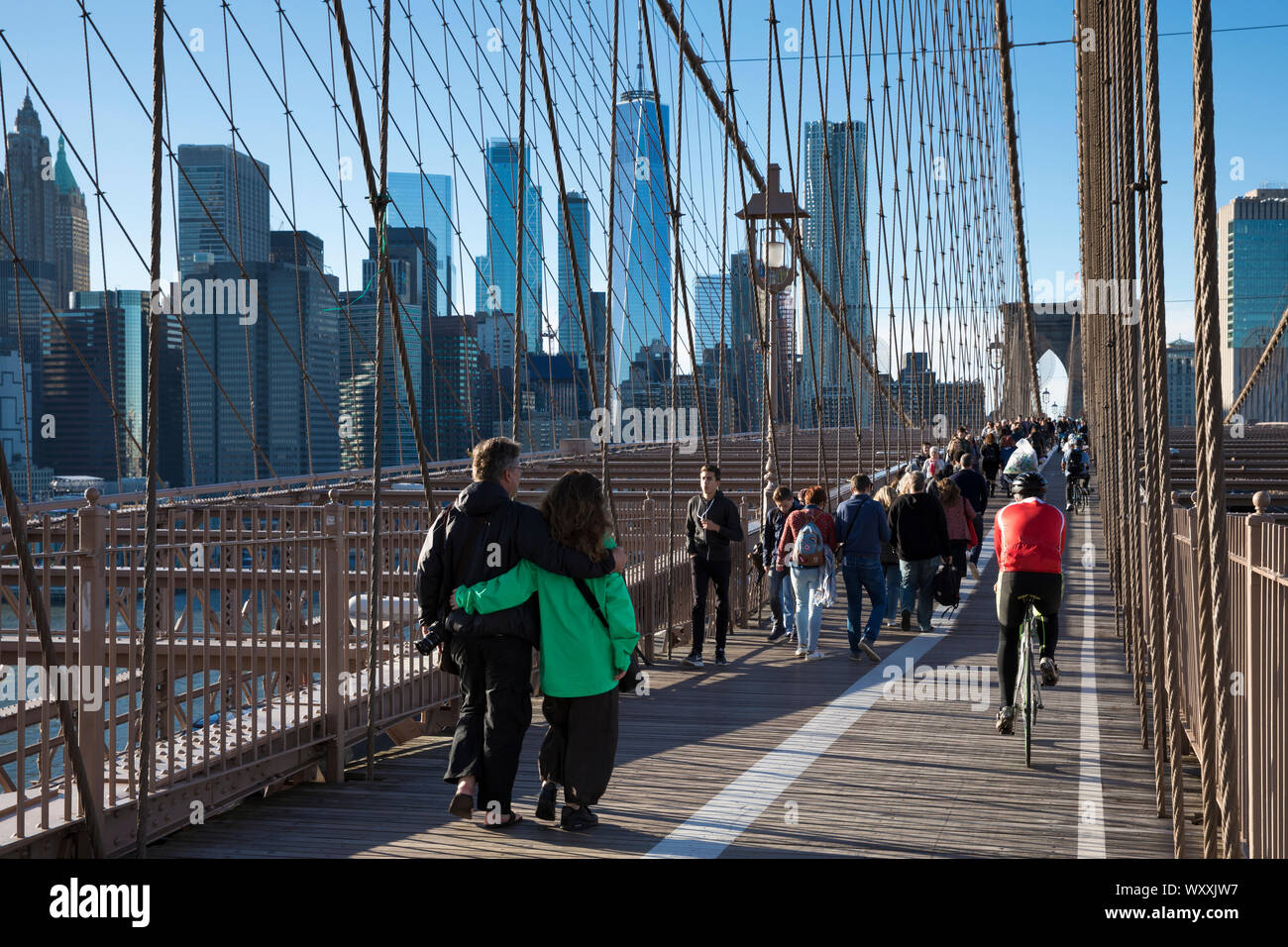 Tourists and local people stroll and cycle across Brooklyn Bridge towards Manhattan, New York City Stock Photo