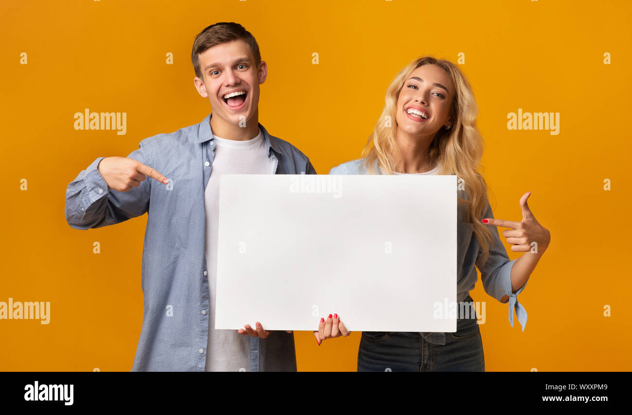 Young people holding blank advertising board and pointing on it Stock ...