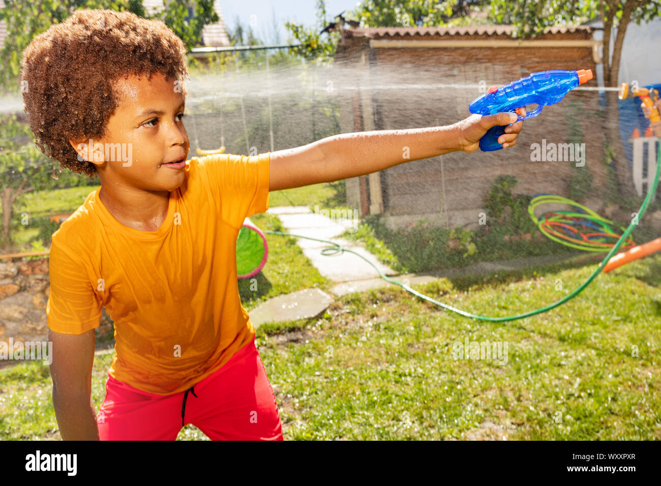 Little Black Boy With Curly Hair And Yellow T Shirt Shoot Water