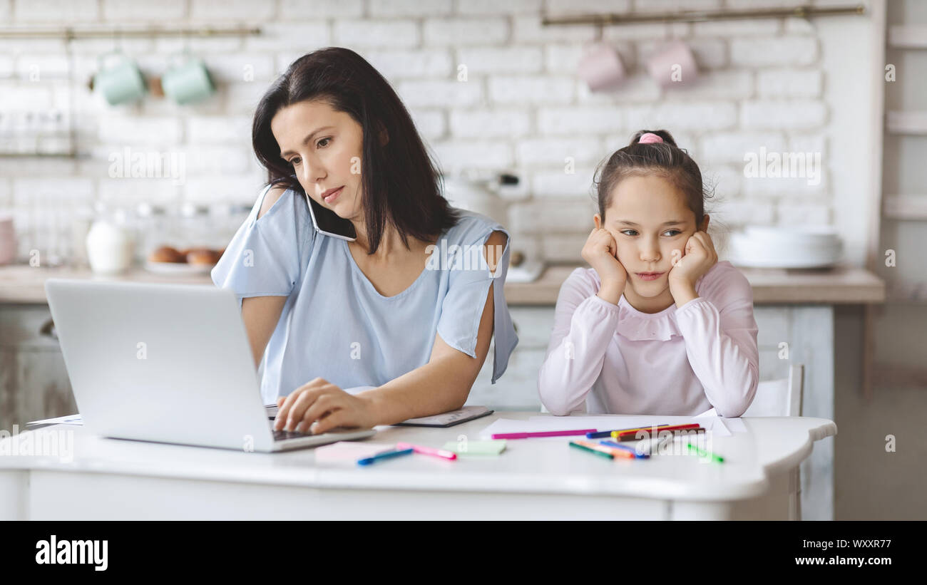 Girl upset with lack of attention while her mother working Stock Photo
