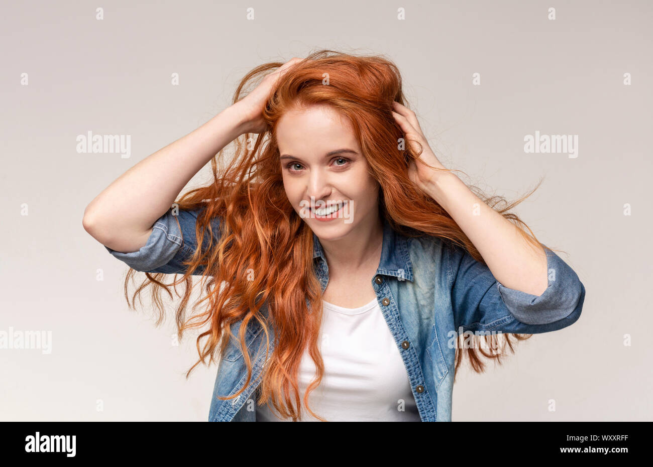 Redhead girl brushing hair with fingers, enjoying her natural look Stock Photo
