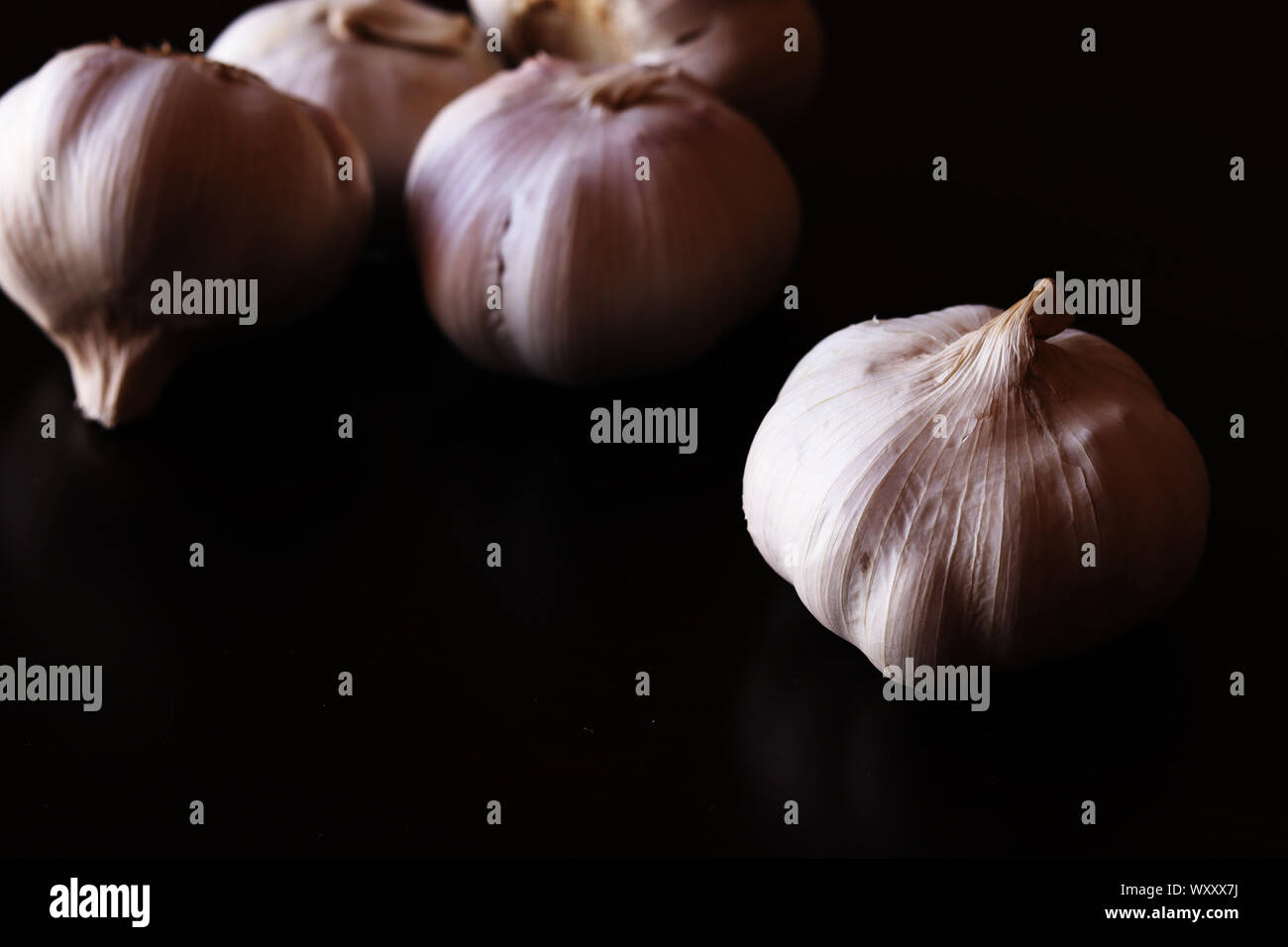 Garlic bulbs against plain black background Stock Photo