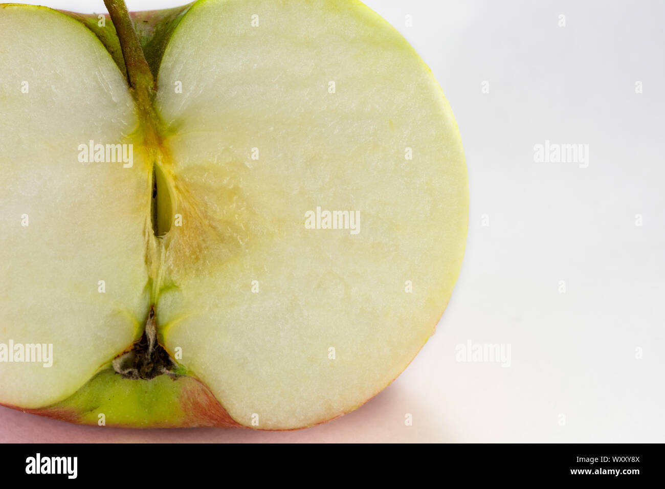 Bright vibrant fresh apple sliced in half. Photography taken on white backgound with macro lens. Stock Photo