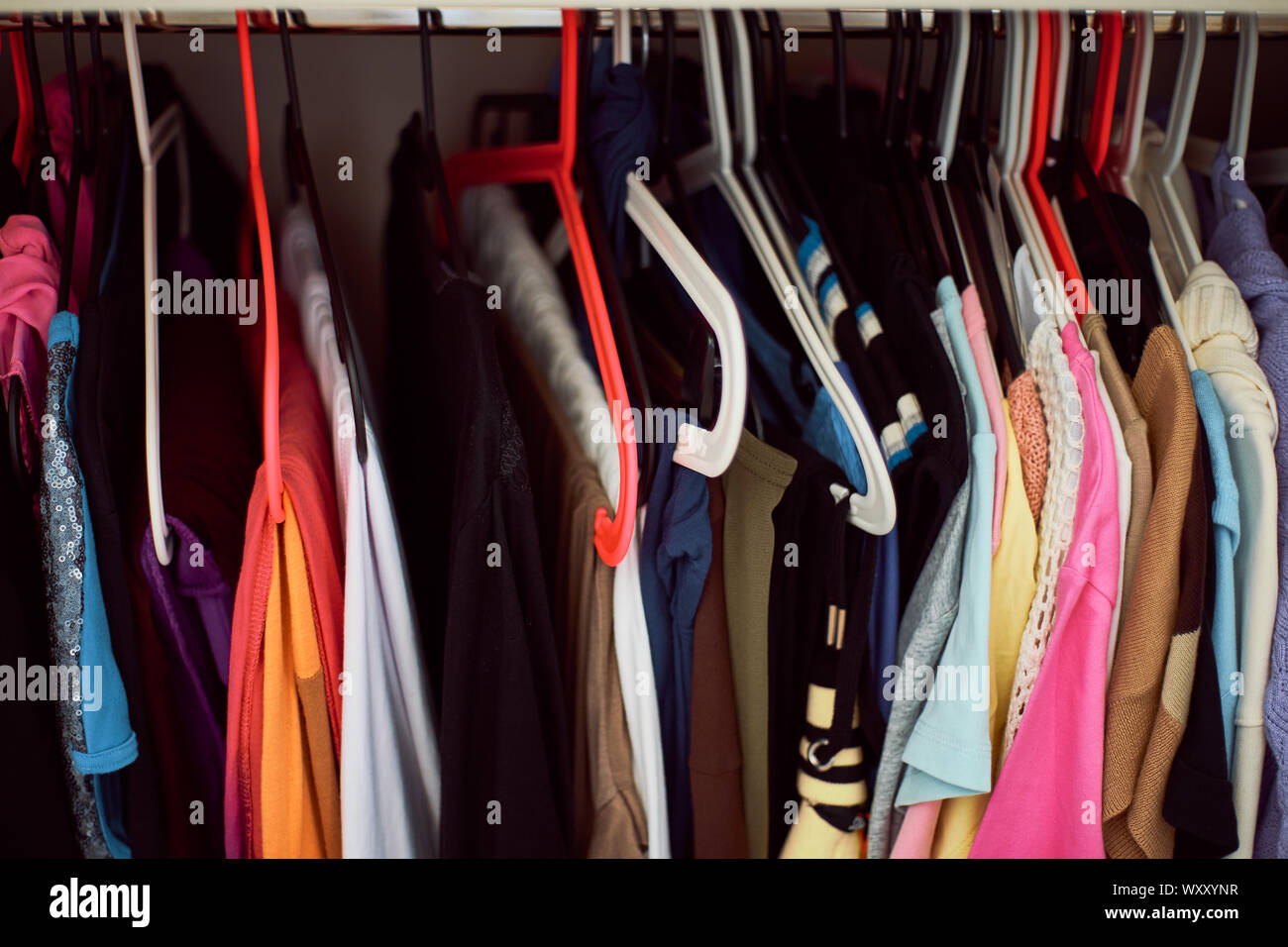 Close-up of a woman's wardrobe with crutches with colored clothes hanging on the coat rack Stock Photo