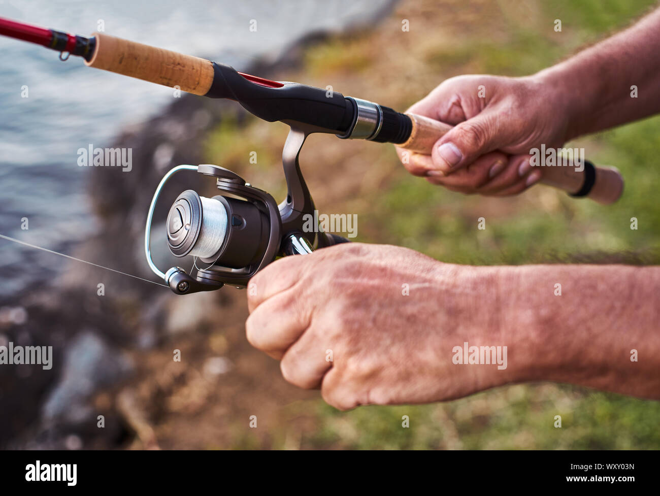 The hands of an adult man holding a sport fishing rod with reel