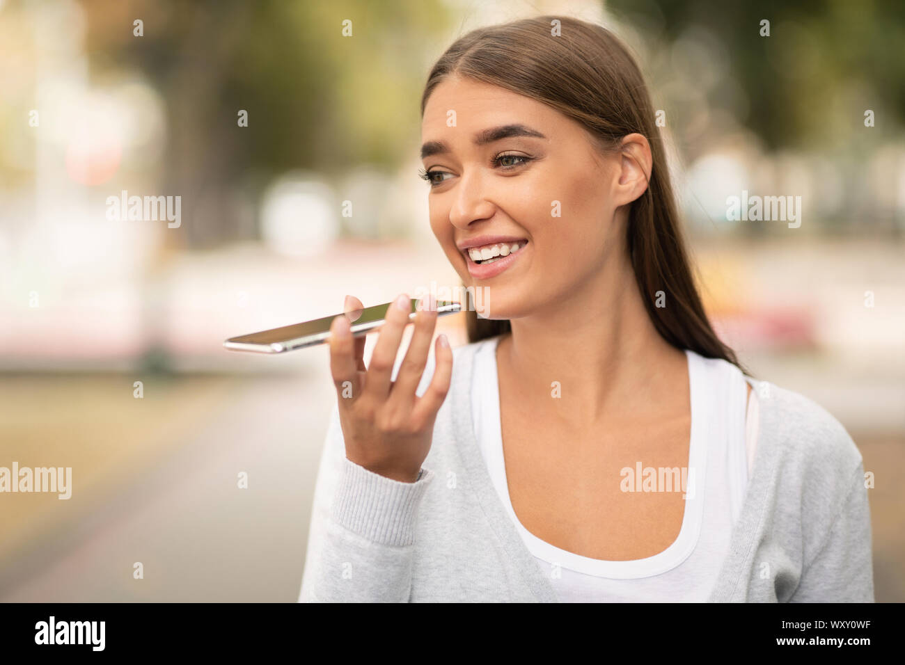 Woman using digital voice assistant on cellphone outdoor Stock Photo