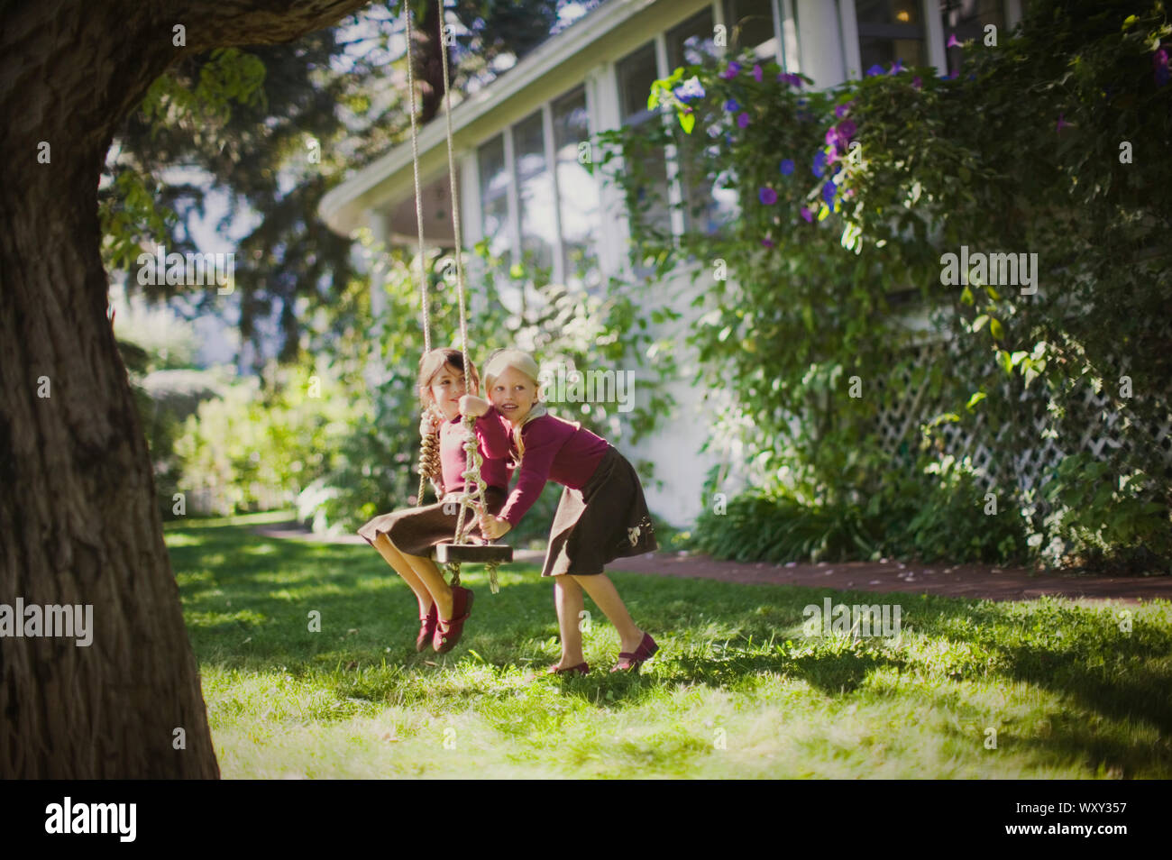 young girl pushes her friend on a swing Stock Photo Alamy