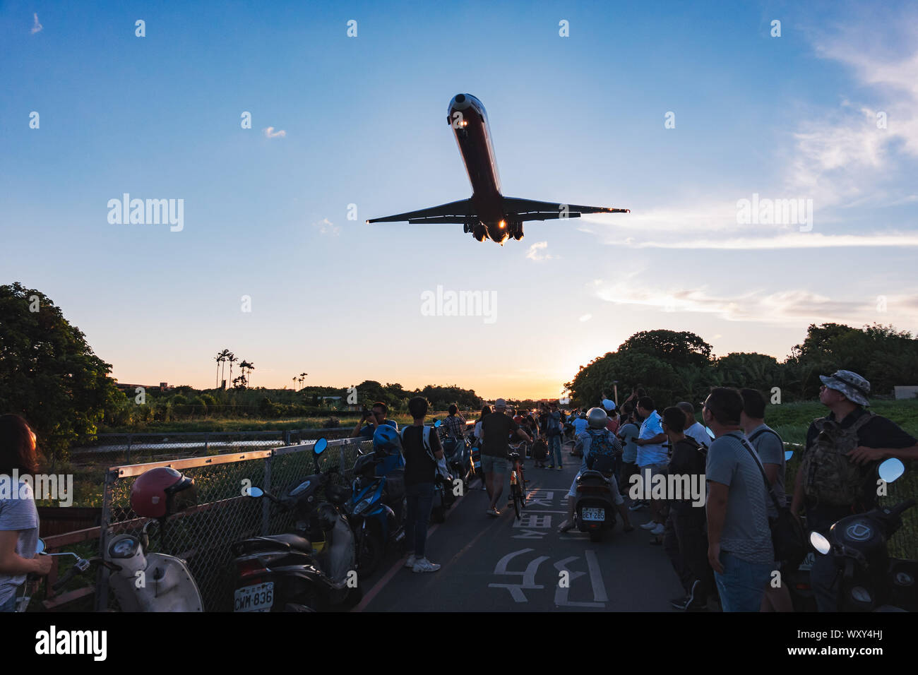 Spectators pose for photos while a McDonnell Douglas MD-82 screams over their heads on approach to Songshan Airport, Taipei Stock Photo