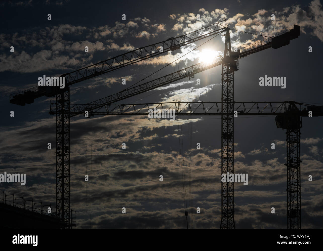 Cranes on a construction site with a cloudy sky during sundown Stock ...