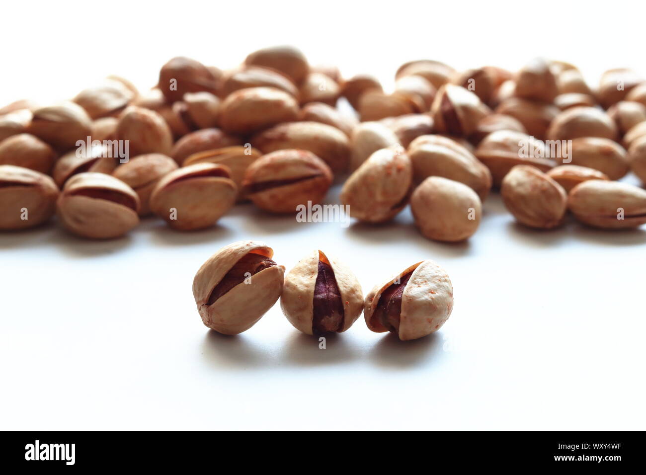 Brown roasted Iranian pistachio nuts in shells on plain white