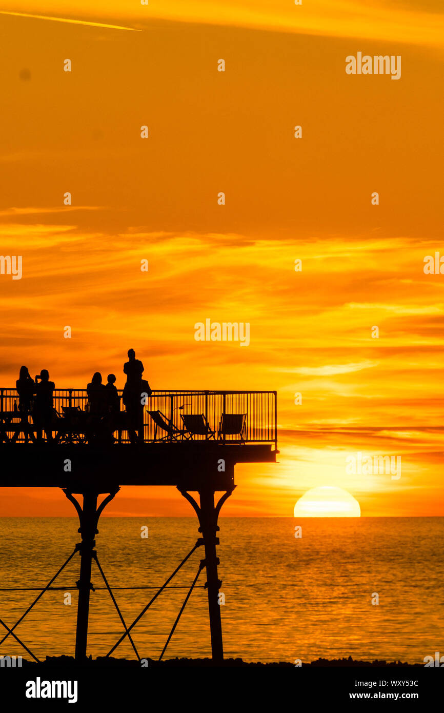 Aberystwyth, UK. 18th Sep, 2019. Aberystwyth Wales UK, Wednesday 18 September 2019 The sun setting gloriously over  Cardigan Bay silhouettes people on the seaside pier at the end of a day of unbroken clear blue skies and warm September sunshine in Aberystwyth ,  as the ‘indian summer’ mini heat-wave continues over much of the souther parts of the UK   Credit: keith morris/Alamy Live News Stock Photo
