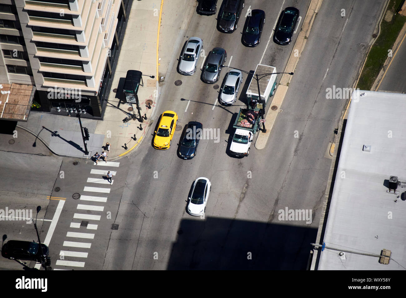 overhead view of cars pulling away from lights with tesla model 3 ev in front at the junction of oak street and north michigan avenue in chicago illin Stock Photo