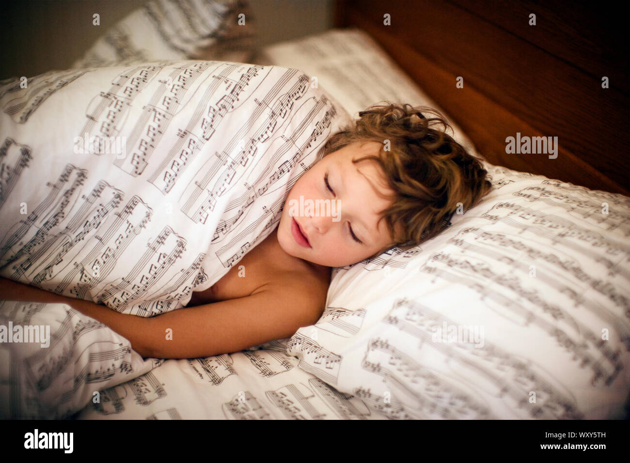 boy sleeps between sheets Stock Photo Alamy
