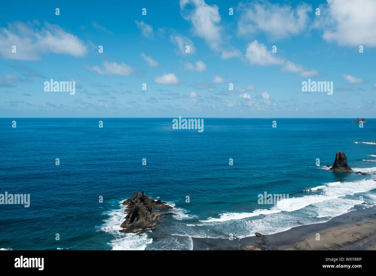 Ocean horizon with blue sky and rocks near beach / coast Stock Photo