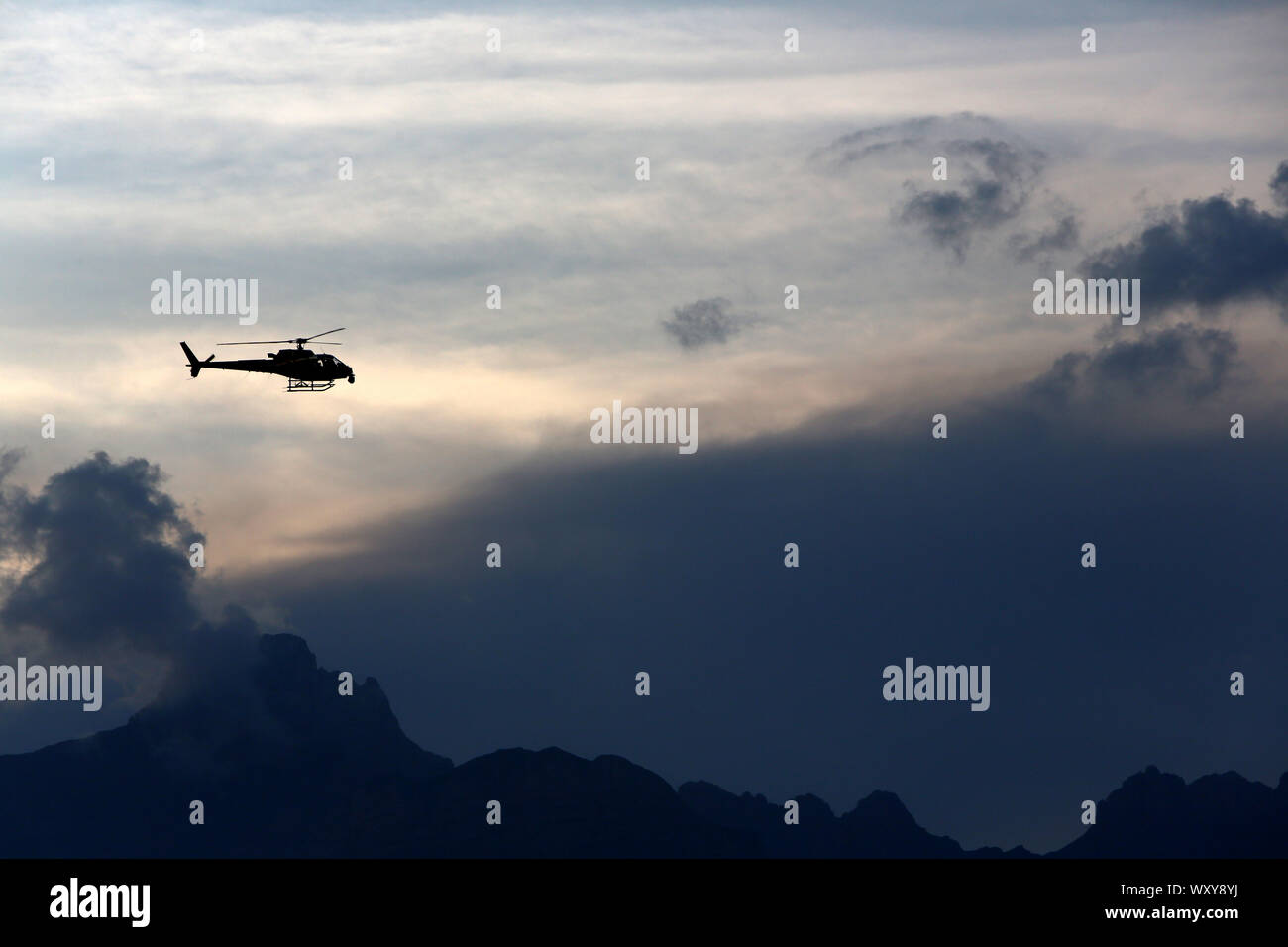 Hélicoptère en vol par temps d'orage au-dessus de la chaîne des Arravis. Haute-Savoie. France. Stock Photo