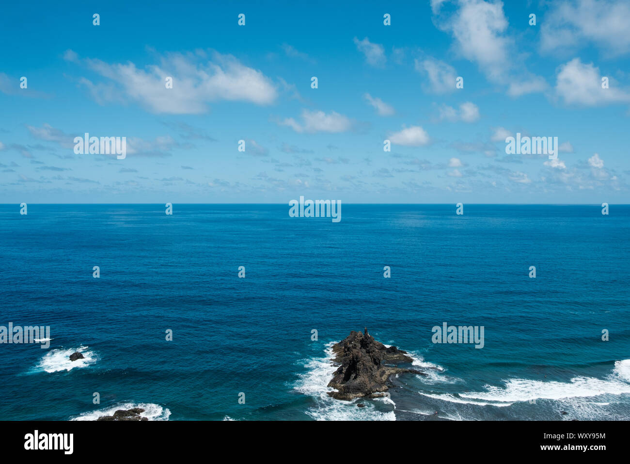 Ocean horizon with blue sky and rocks near beach / coast Stock Photo