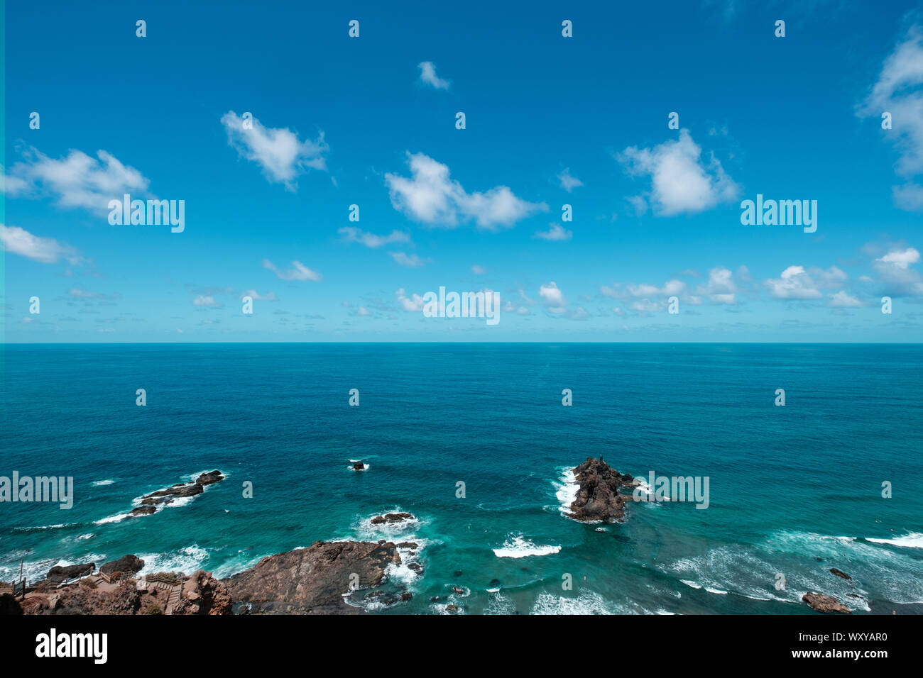 Blue sky above ocean horizon on sunny summer day at rocky coast Stock Photo
