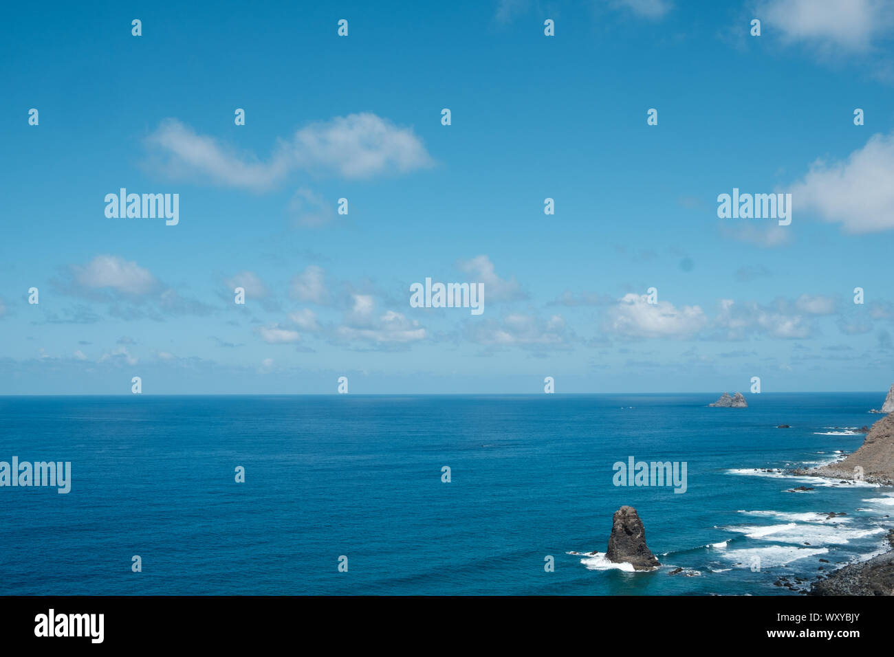 Blue sky above ocean horizon on sunny summer day at rocky coast Stock Photo