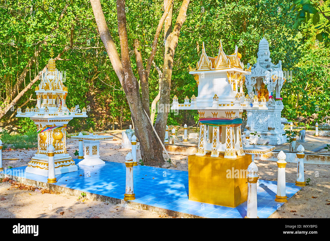 The small Buddhist shrine with gilt mondops (pavilions), decorated with fine patterns and molding, located among the trees on sand beach of Ao Nang, K Stock Photo