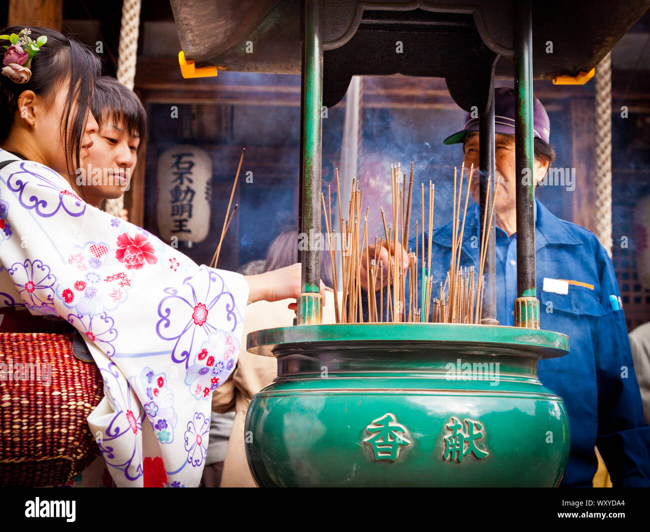 Japanese ritual of lighting incense stick outside temple Stock Photo