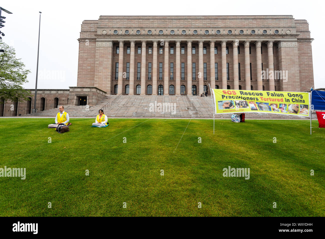Falun Gong protest in front of Parliament House, Helsinki, Finland 2019. Banner reads: Rescue Falun Gong Practitioner Tortured in China Stock Photo