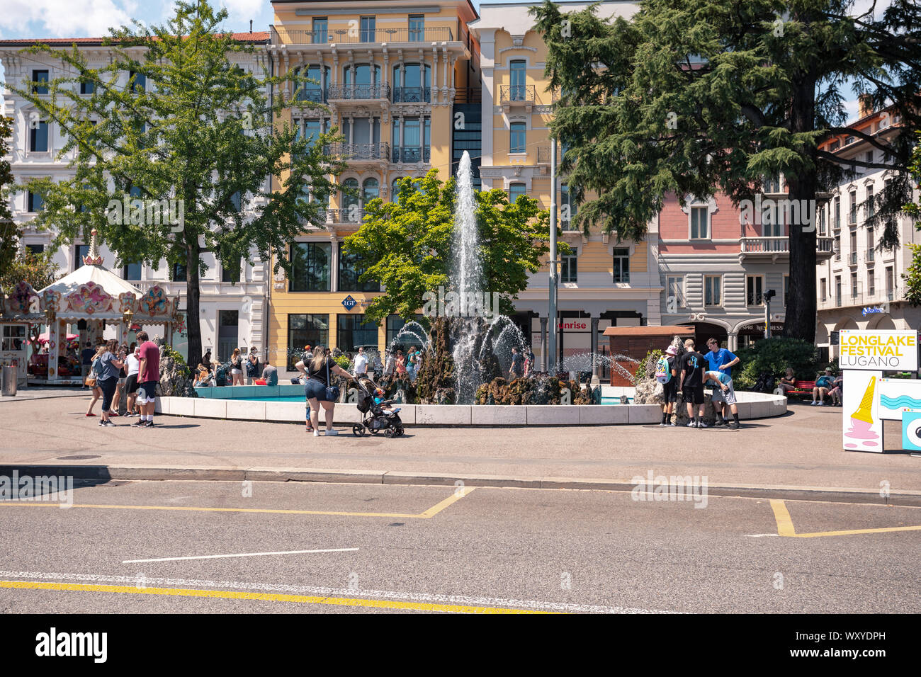 People relaxing near the fountain  from the square Alessandro Manzoni in front of Lgt Private Bank in the center of Lugano city, Switzerland Stock Photo