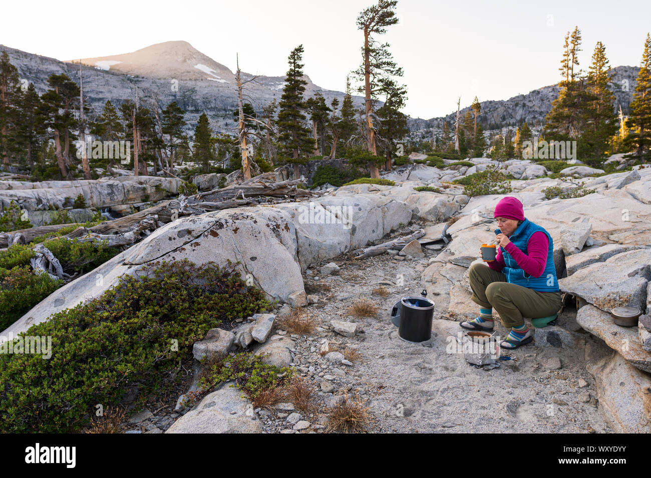 Backpacking off trail in Desolation Wilderness at Ropi Lake camp cooking with pyramid peak in background. Stock Photo
