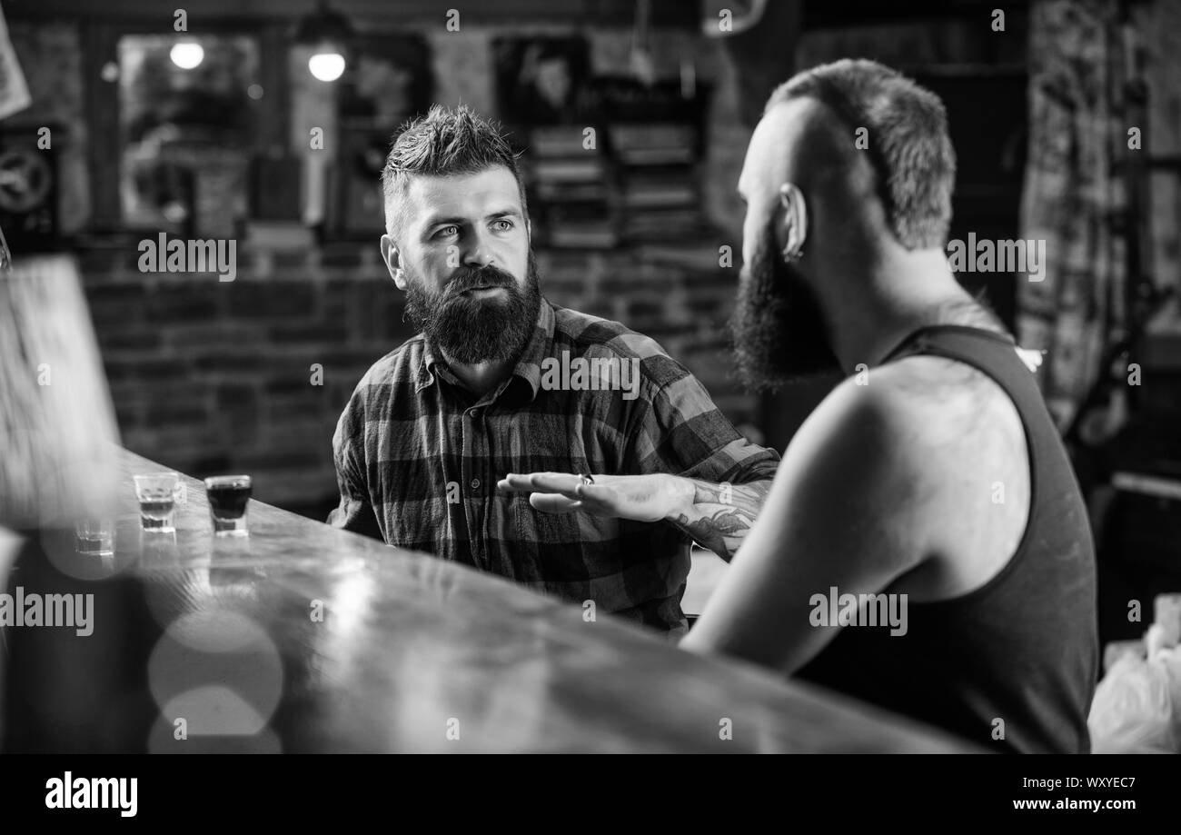 Friday relaxation in bar. Friends relaxing in bar or pub. Soulmates drunk conversation. Hipster brutal bearded man spend leisure with friend at bar counter. Men relaxing at bar. Strong alcohol drinks. Stock Photo