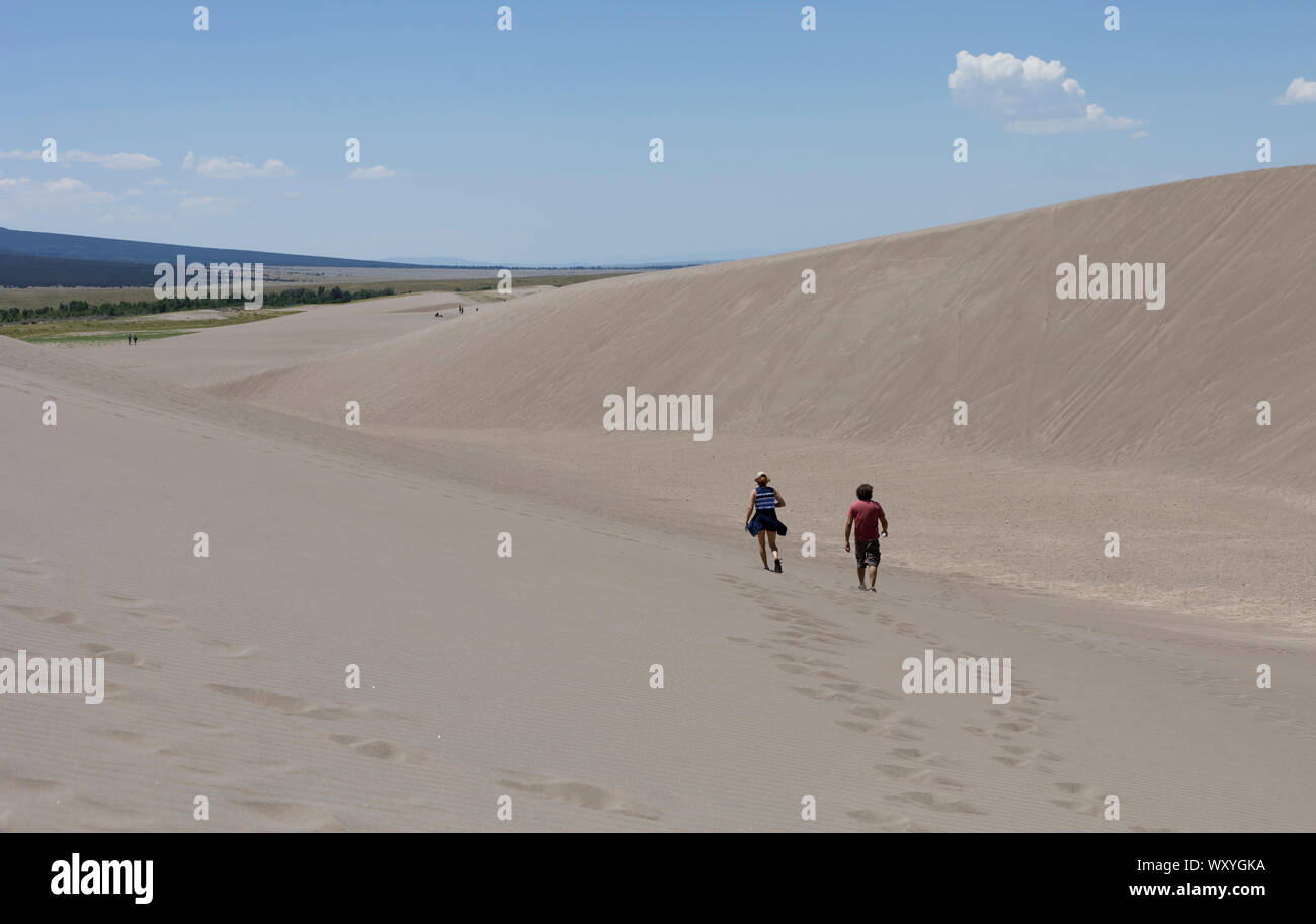 Hikers wander in the dunes at Great Sand Dunes National Park during summer in Colorado. Stock Photo